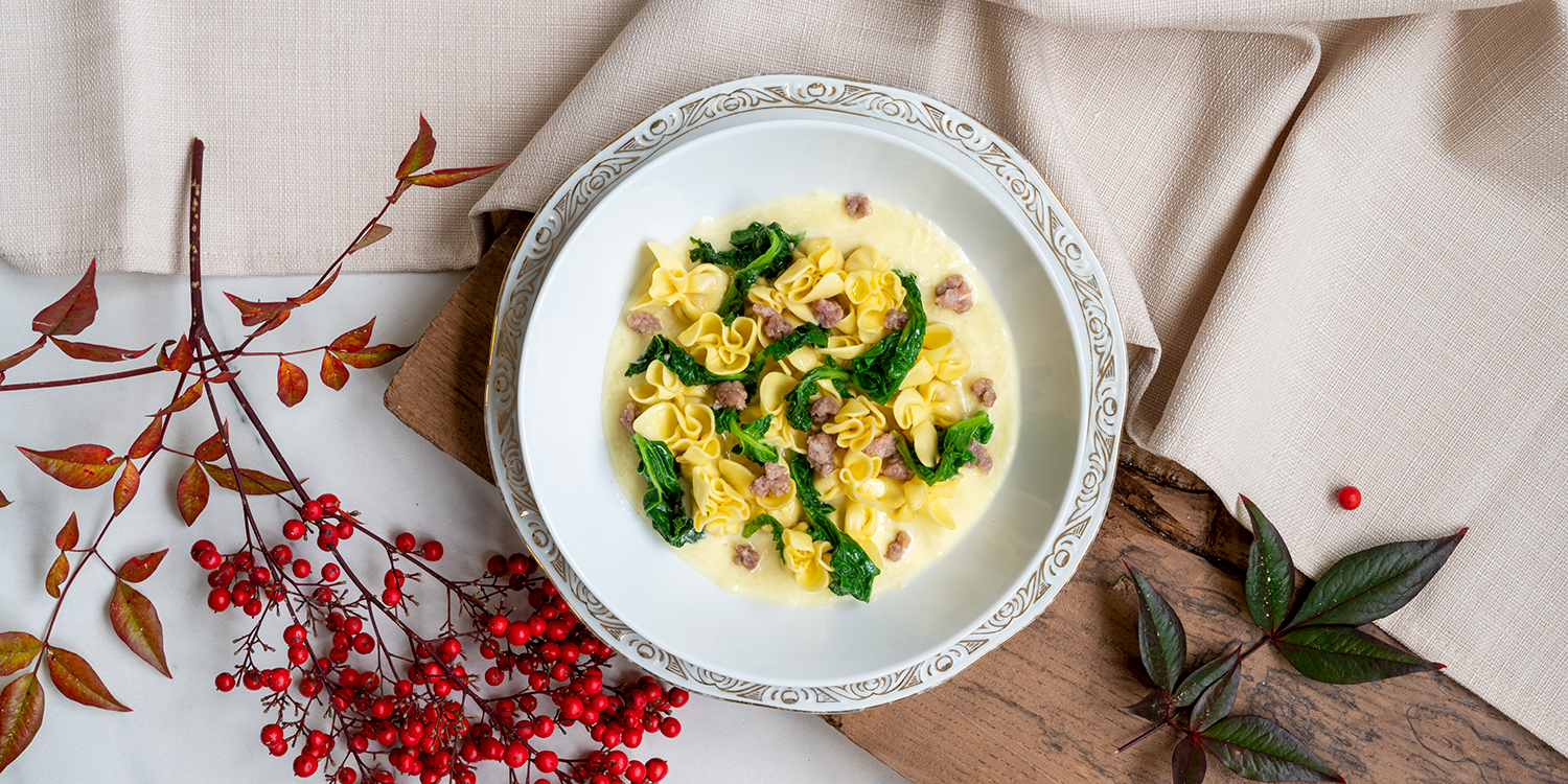 Perline al prosciutto crudo: pasta con cime di rapa e salsiccia in briciole su crema di Fontina